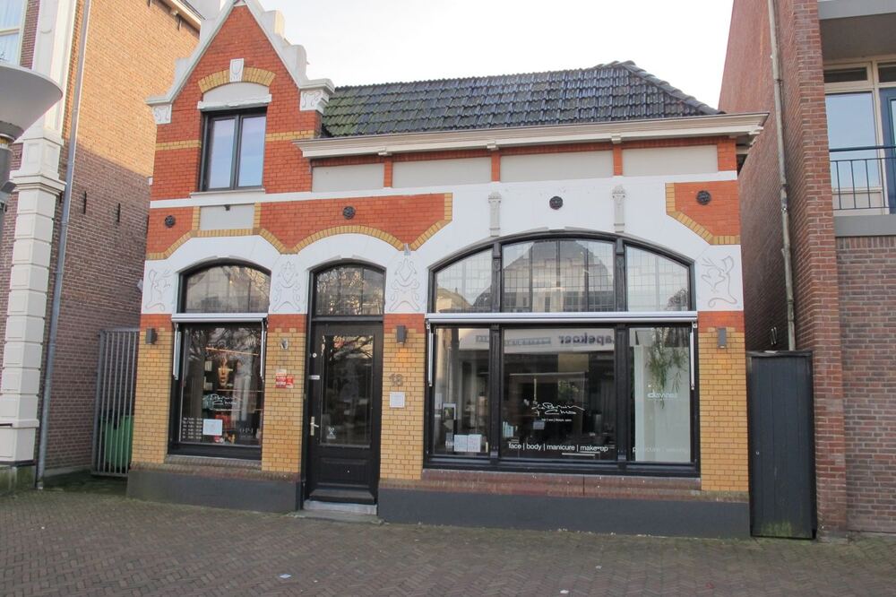 Winkelpand in jugendstil met rood-gele baksteengevel en gebogen etalageramen aan de Midstraat in Joure